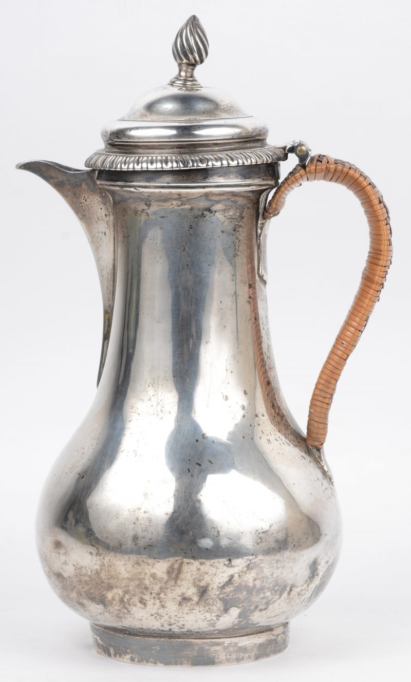 Sterling zilveren George III koffiepot met gevlochten rieten handvat. Beursvormig met korte tuit. Deksel sober versierd met ribbelrand en getorste dekselknop. Meesterkeur en keuren van Londen voor 1757. Drie deuken onderaan de buik.