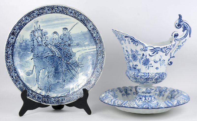 Twee stuks blauw en wit aardewerk, bestaande uit een sierbord van Boch en een schenkkan met schotel. De tweede beschadigd.