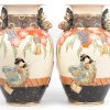 Een paar vazen van Satsuma-aardewerk met een decor van geisha’s in reliëf en met Fo-honden als handvatten. Onderaan gemerkt.