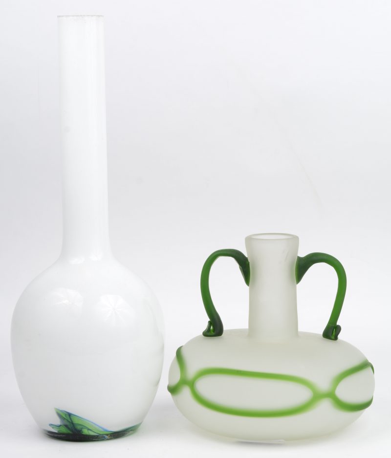 Twee verschillende glazen vazen, waarbij één gesatineerde met groen decor en handvatten en één langerekte witte met groene versiering in de voet. De tweede met randslijtage in de hals.