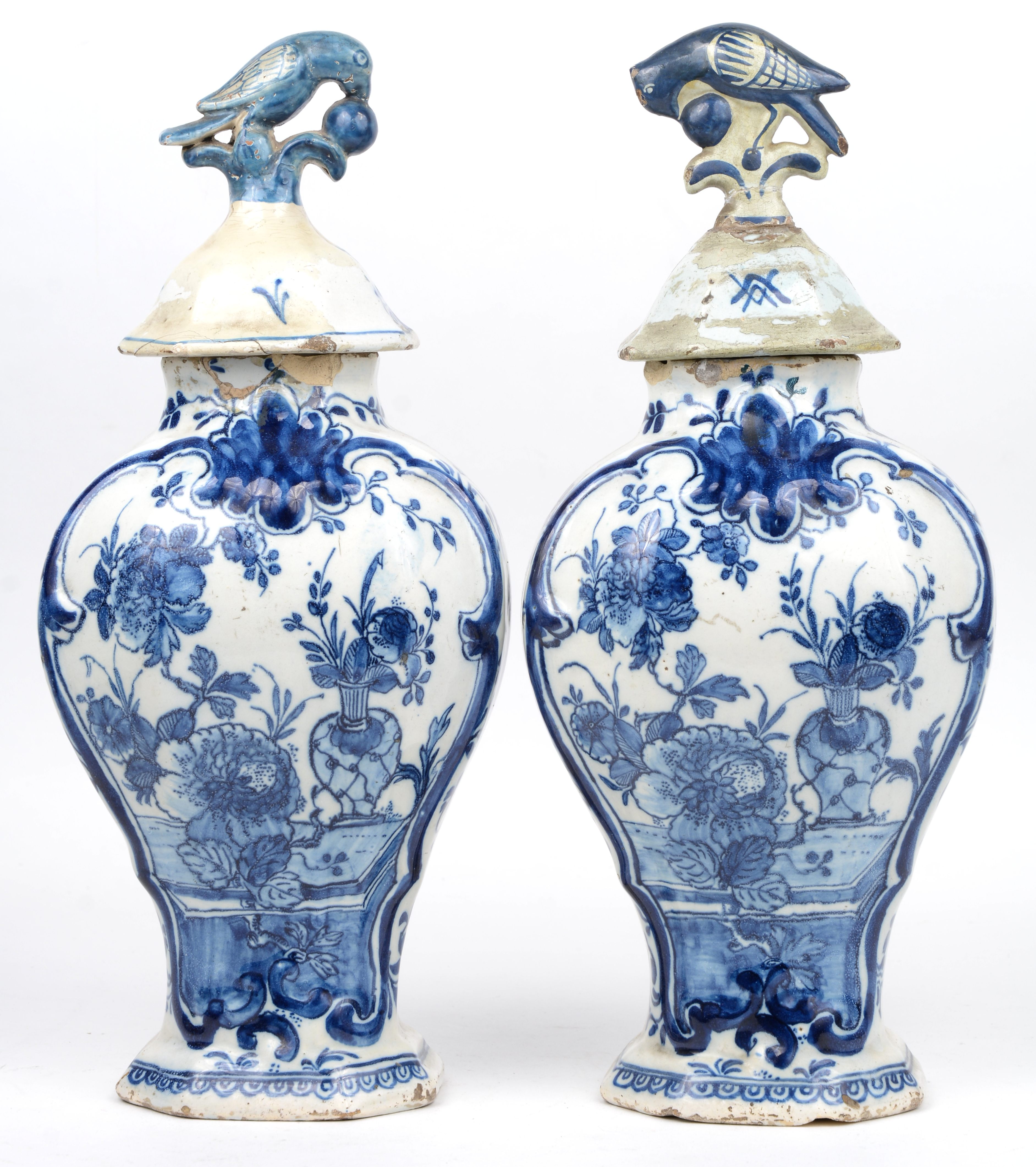 Een paar dekselvazen in Lodewijk XV-stijl in blauw en wit versierd met bloementafels in uitsparingen. Delft, XVIIIde eeuw. Merk van de Clauw. Letsels herstelde deksels. – Jordaens N.V. Veilinghuis