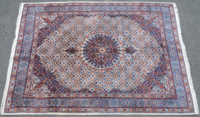 Een handgeknoopt Perzisch karpet van wol en katoen.