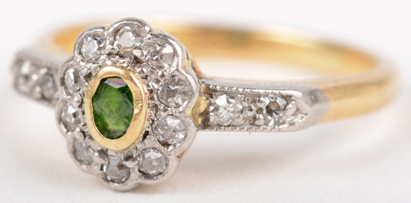 Een 18 K wit en geelgouden ring bezet met diamanten met een gezamenlijk gewicht van +- 0,20 ct. en een smaragd van +- 10 ct. Maat 52.