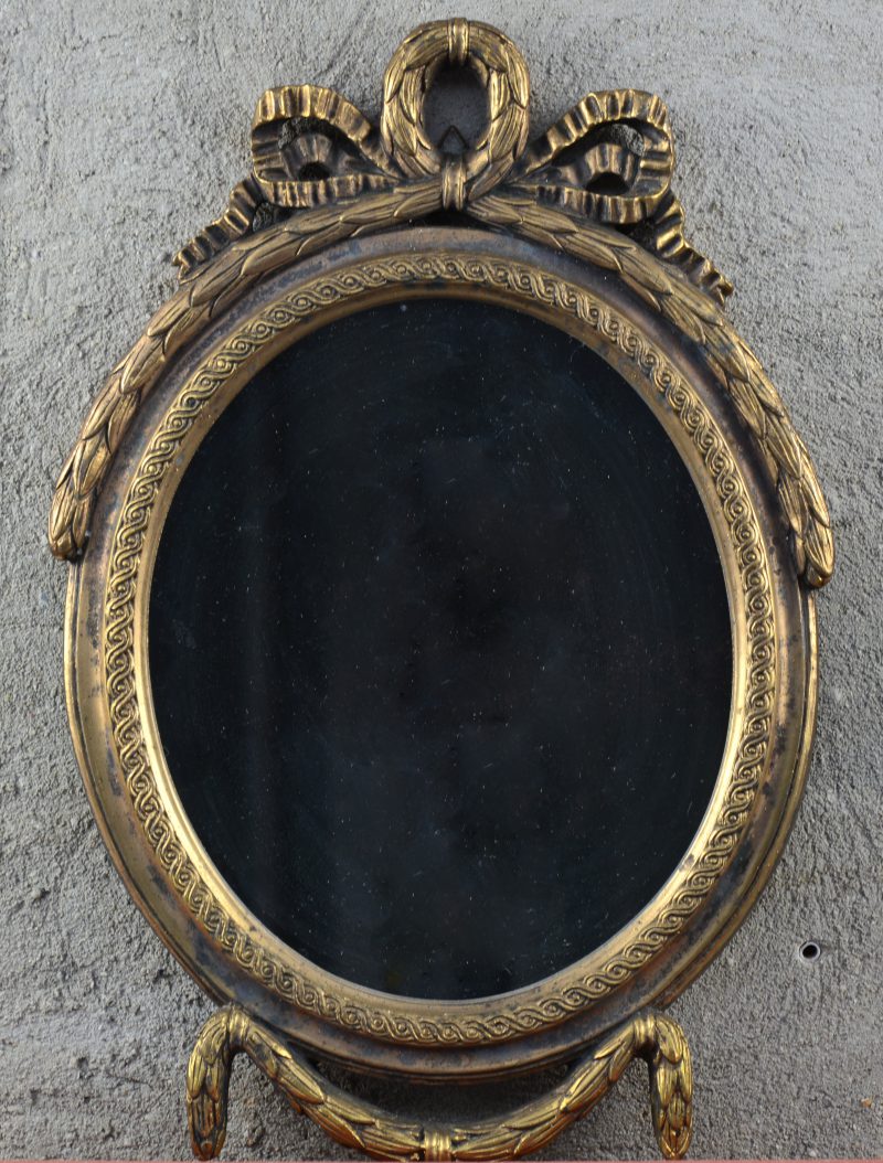 Een goudgepatineerd ovaal houten spiegeltje in Lodewijk XVI-stijl.