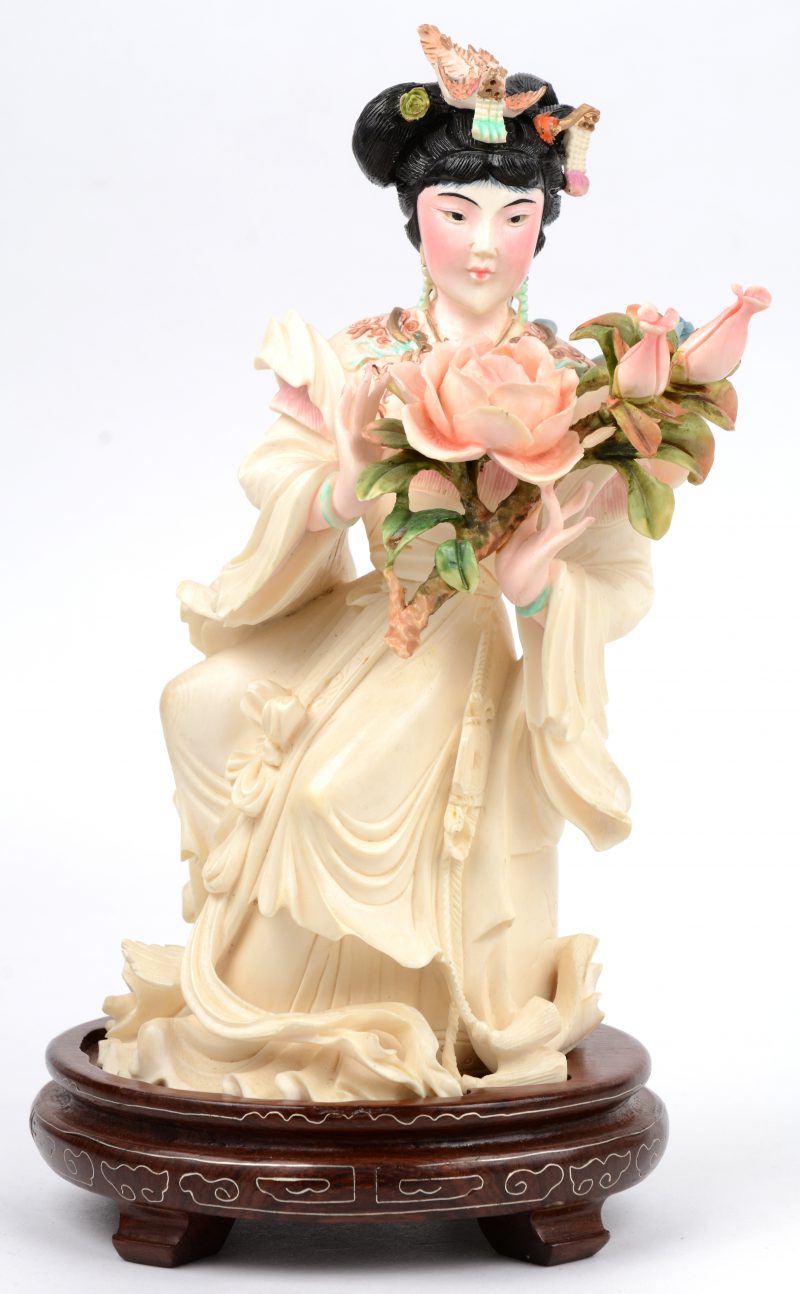“Vrouw met rozen”. Een fijn gesculpteerde en gepolychromeerde ivoren groep. Onderaan gesigneerd. China, medio XXe eeew. Op houten sokkel