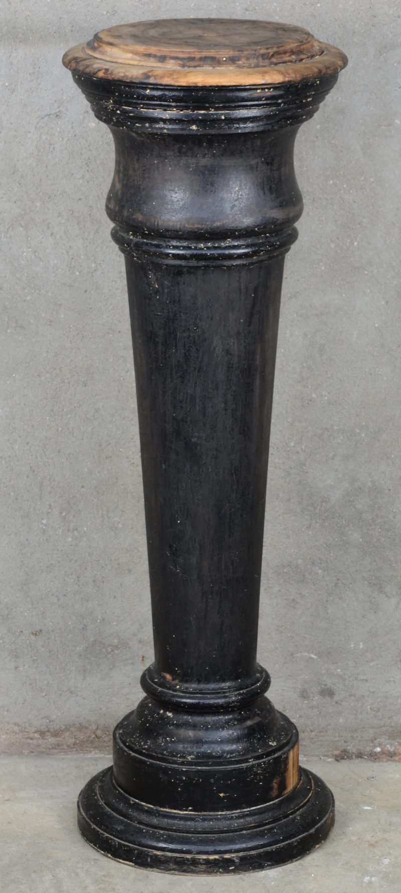 Een ronde, obconische houten zuil, deels zwartgebeitst.