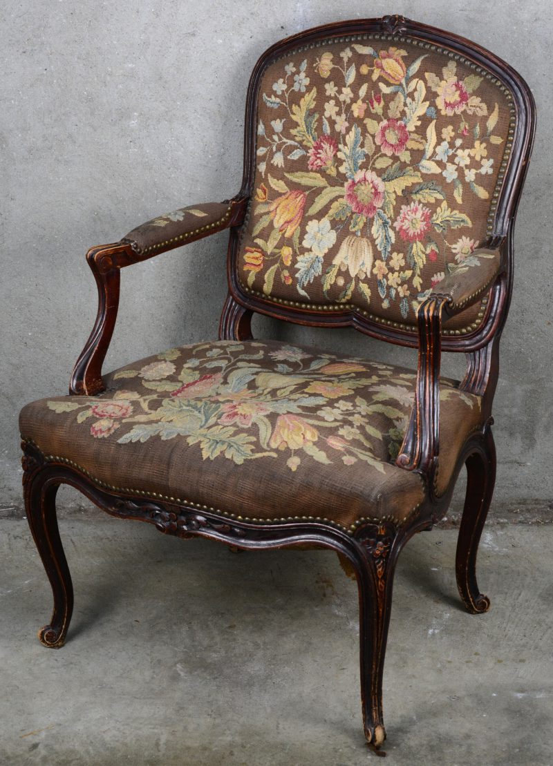 Een gebeeldhouwde fauteuil à la reine, bekleed met naaldwerk.