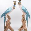 Een paar kandelaars van brons en meerkleurig porselein in de vorm van papegaaien.
