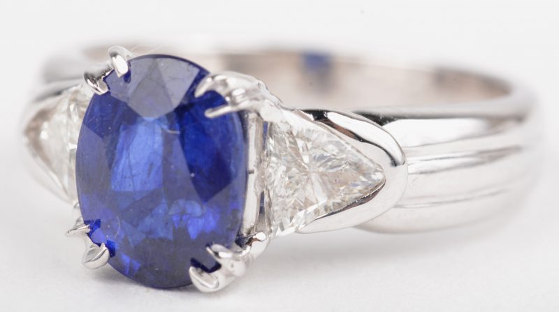 Een 18 K witgouden ring bezet met een centrale saffier van +- 2,10 ct. en diamant princessen met een gezamenlijk gewicht van +- 0,50 ct.