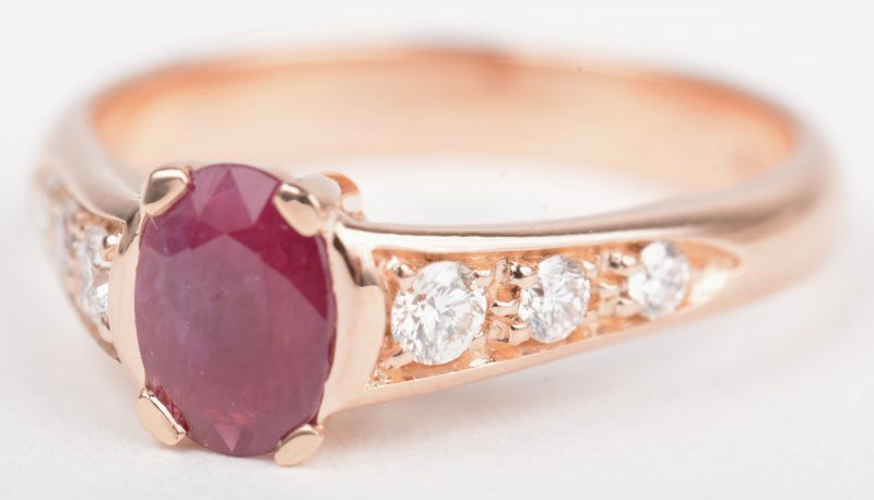 Een 18 K roze kleurige gouden ring bezet met briljanten met een gezamenlijk gewicht van +- 0,26 ct. en een centrale robijn van +- 0,55 ct.