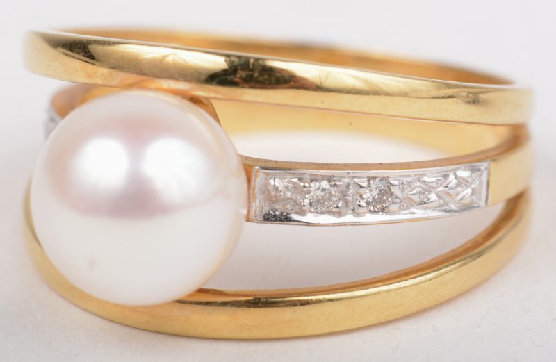 Een 18 K geelgouden ring bezet met briljanten met een gezamenlijk gewicht van +- 0,08 ct. en een parel.