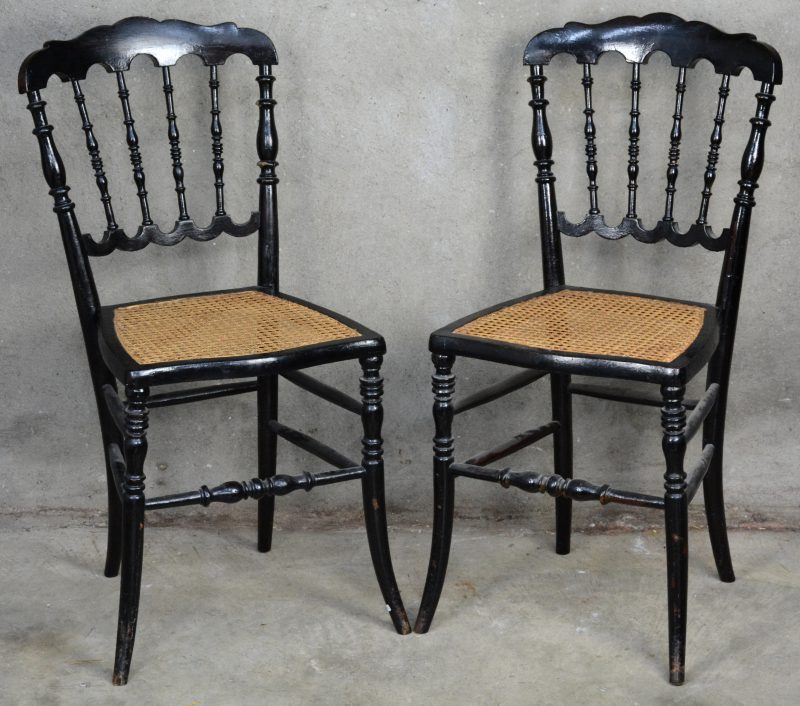 Een paar zwartgelakt houten stoeltjes met gecanneerde zit.