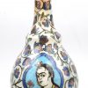 Een Iznik langhalsvaas van geglazuurd steengoed, versierd met portretten in uitsparingen, omgeven door bloemenguirlandes. Sporen van ovenvuur.