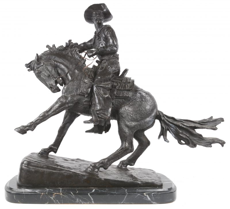 “The Cowboy”. Ruiter te paard. Bronzen beeld naar het werk van Frederic Remington. Op marmeren voetstuk. Recente geut. (Kleine restauratie)
