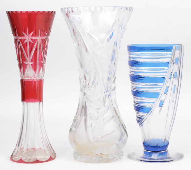 Een lot van drie verschillende geslepen kristallen glazen, waarbij één met blauw decor, een met rood decor en een kleurloze.