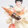 “Vrouw met instrument”. Een fijn gesculpteerd en gepolychromeerd ivoren beeldje op houten sokkel. China, medio XXe eeuw.