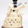 “Vrouw met instrument”. Een fijn gesculpteerd en gepolychromeerd ivoren beeldje op houten sokkel. China, medio XXe eeuw.