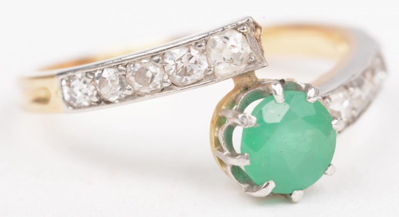 Een 18 K wit en geelgouden ring bezet met een briljanten met een gezamenlijk gewicht  van +- 0,30 ct. en een smaragd van +- 0,50 ct.