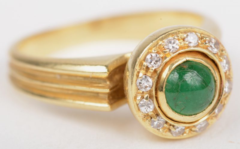 Een 18 K geelgouden ring bezet met briljanten met een gezamenlijk gewicht van +- 0,15 ct. en een smaragd cabochon van +- 0,25 ct.