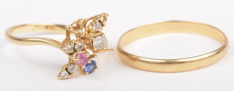Een 18 K geelgouden trouwring en 18 K geelgouden bloemvormige ring bezet met fantasiestenen. (één steentje ontbreekt).