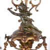 Een driedelig schouwgarnituur van brons in eclectische stijl, bestaande uit een pendule en twee vierarmige kandelaars.