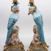 Een paar kandelaars van meerkleurig porselein en verguld brons in de vorm van papegaaien. Apocrief gemerkt onderaan.