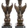 Een paar bronzen kandelaars in de vorm van sfinxen. Op zwart marmeren sokkels.