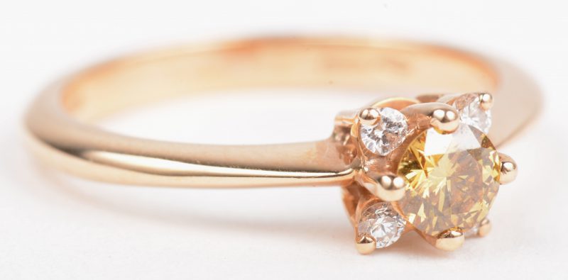Een 18 K roze gouden ring bezet met vier kleine briljantjes en een centrale Fancy diamant van +- 0,30 ct.