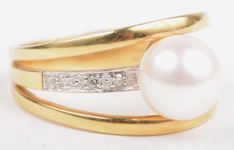 Een 18 K wit en geelgouden ring bezet met een briljanten met een gezamenlijk gewicht van +- 0,08 ct. en een parel.