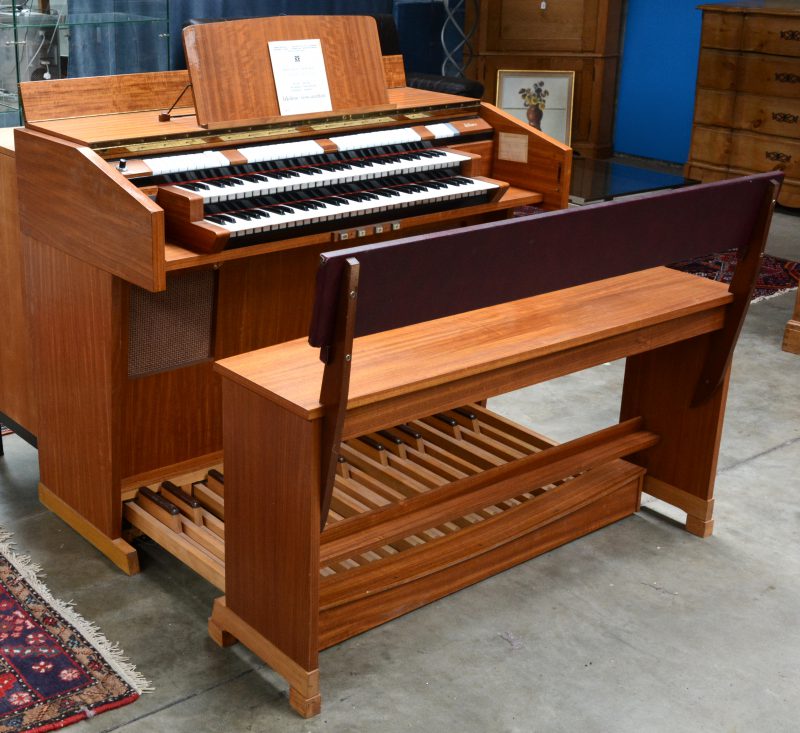 Een elektrisch orgel met diverse registers, dubbel klavier en afsluitbaar. Met bijhorende bank.
