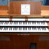 Een elektrisch orgel met diverse registers, dubbel klavier en afsluitbaar. Met bijhorende bank.