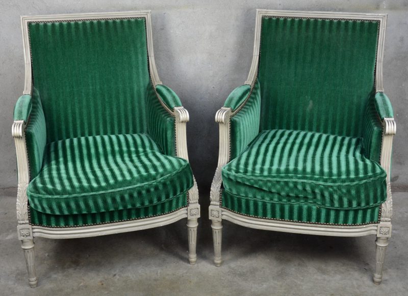 Een paar grijsgepatineerde fauteuils in Lodewijk XVI-stijl met groen fluwelen bekleding.