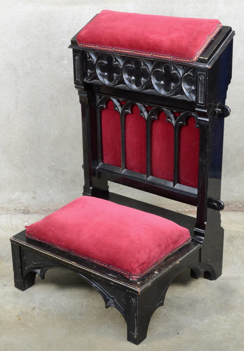 Een antieke kerkstoel van gesculpteerd en zwartgelakt hout in gotische stijl.