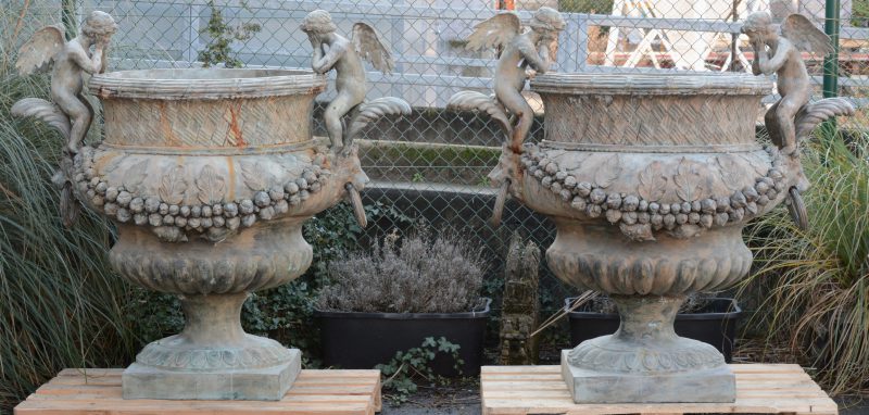 Een paar grote bronzen tuinvazen in barokke stijl versierd met engelen en guirlandes.