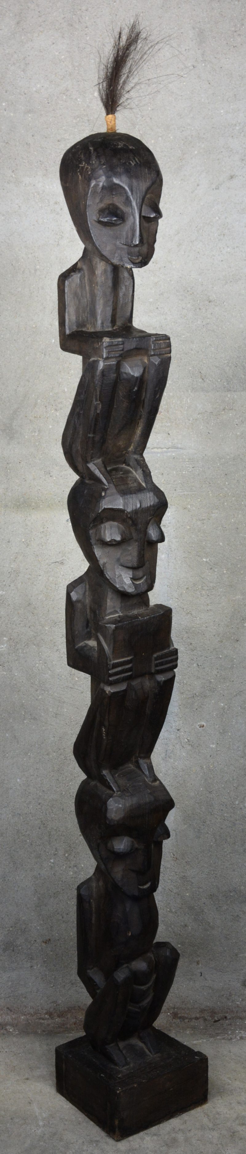 Een Afrikaans houten beeld met drie op elkaar zittende figuren.