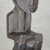 Een Afrikaans houten beeld met drie op elkaar zittende figuren.