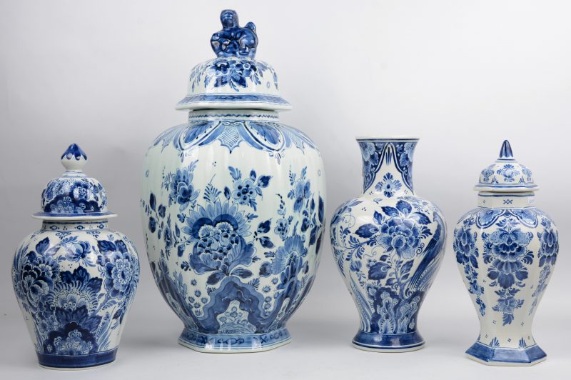 Een lot van vier verschillende vazen van Delfts aardewerk, waarvan drie dekselvazen. De laagste dekselvaas met beschadiging aan de rand.
