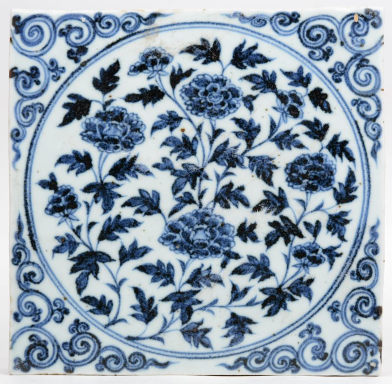 Een Chinees porseleinen tegel met een blauw op wit bloemendecor.