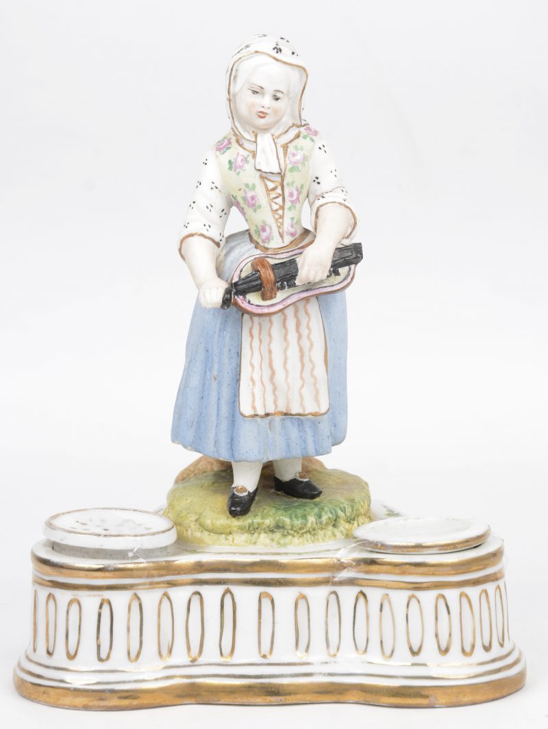 Een inktpot van deels verguld Brussels porselein, getooid met een meisje met draailier van meerkleurig biscuit. Gaaf.