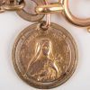 Een 18 K geelgouden hanger “Santa Teresia a Jesu infante”. +- 2,50 g. aan een plaqué schakelarmband.