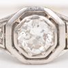 Een 18 K witgouden ring bezet met twee diamant roosjes en een centrale diamant van +- 0,40 ct.