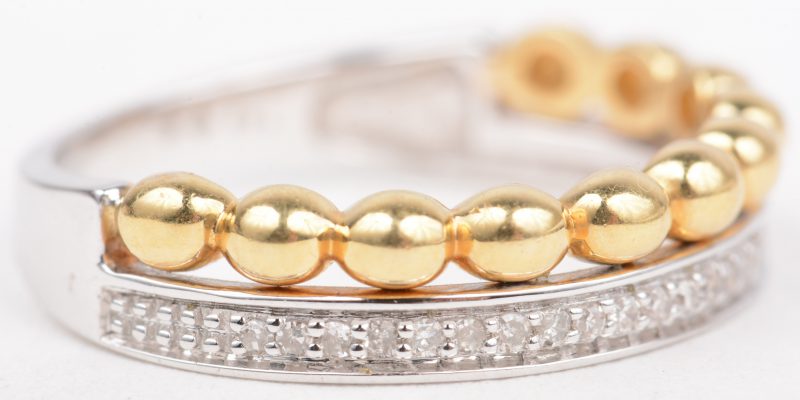 Een 18 K wit en geelgouden ring bezet met briljanten met een gezamenlijk gewicht van +- 0,12 ct.