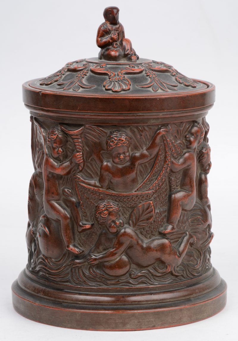Een tabakspot van terracotta, versierd met een reliëfdecor van putti. Onderaan gemerkt ‘F.G.’.