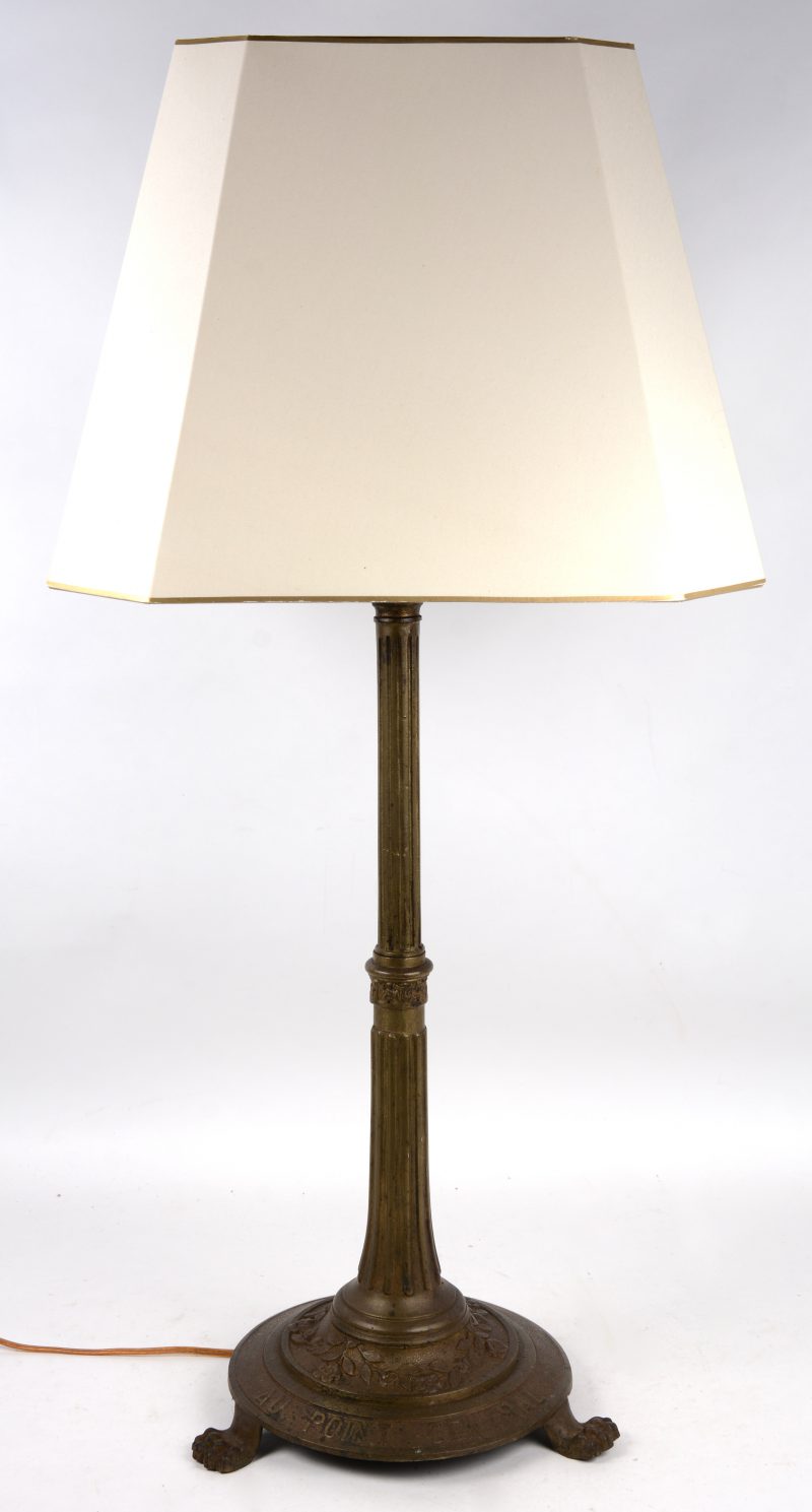 Een grote bronzen tafellamp op klauwpootjes en met opschrift ‘Au point central”.