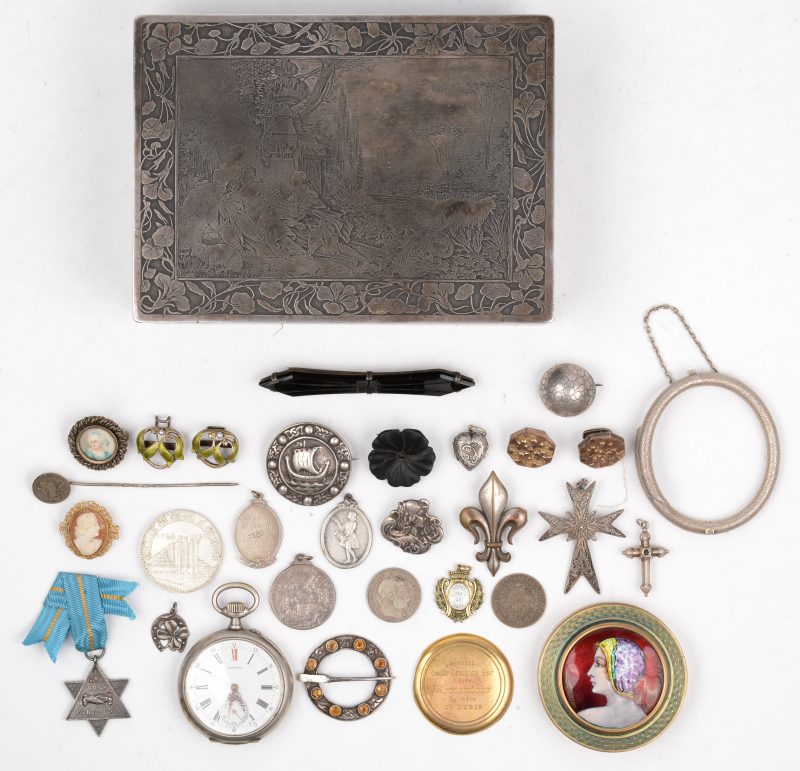 Een rechthoekige metalen doos met daarin fantasiejuwelen, een zakhorloge een poederdoosje met emailversiering, een zilveren munt van 50 BEF (NMBS 100 jaar), armband en broches enz.