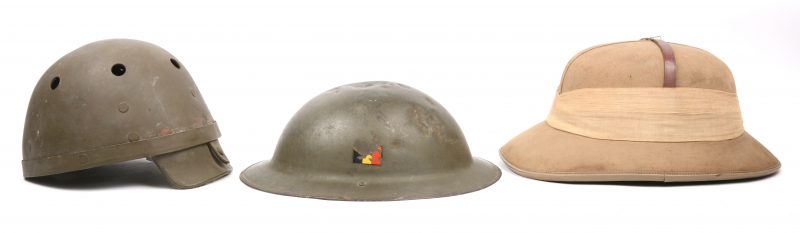 Een lot van drie oude helmen, bestaande uit een tropenhelm, een tankhelm en een Belgische legerhelm.