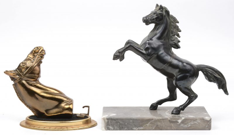 Een lotje bestaande uit een steigerend paardje van brons op grijs marmeren sokkel en een horlogehanger met koperen paardenhoofd.