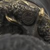 Een adelaar van donker gepatineerd brons op zwart stenen sokkel.