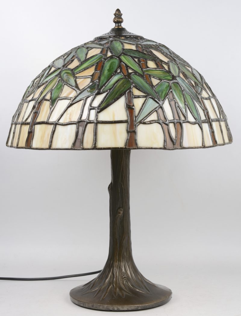 Een bronzen lampenvoet mt kap van glas in lood in de stijl van Tiffany.