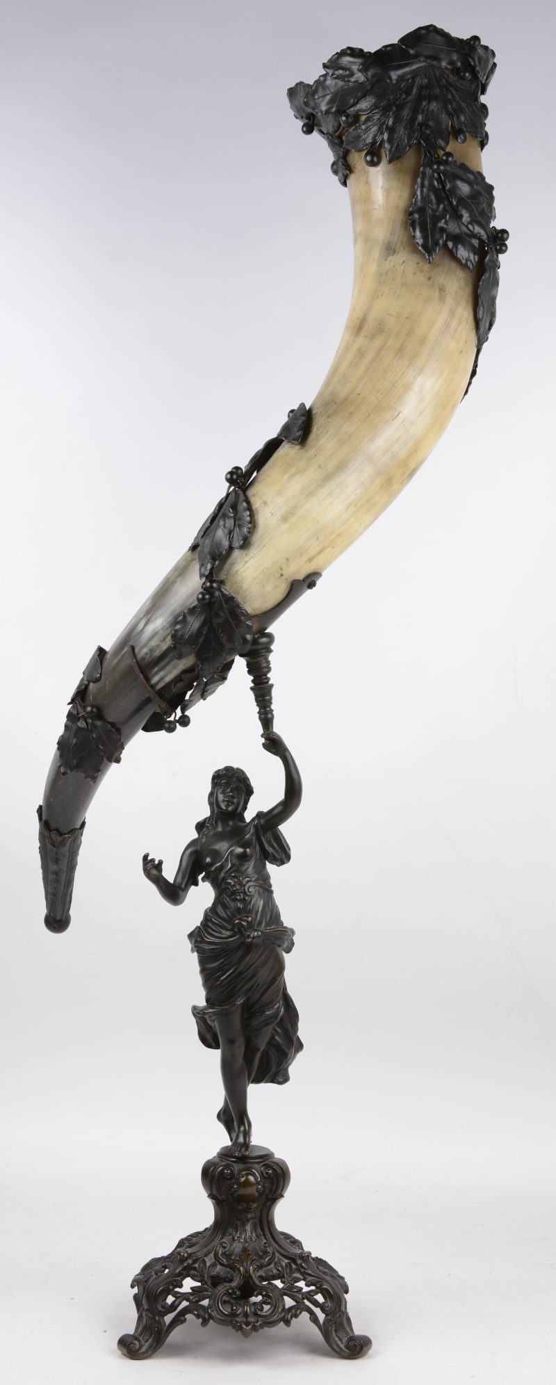 Een grote rundshoorn in gepatineerd messingen voet gedragen door een vrouwenfiguur en versierd met bladeren